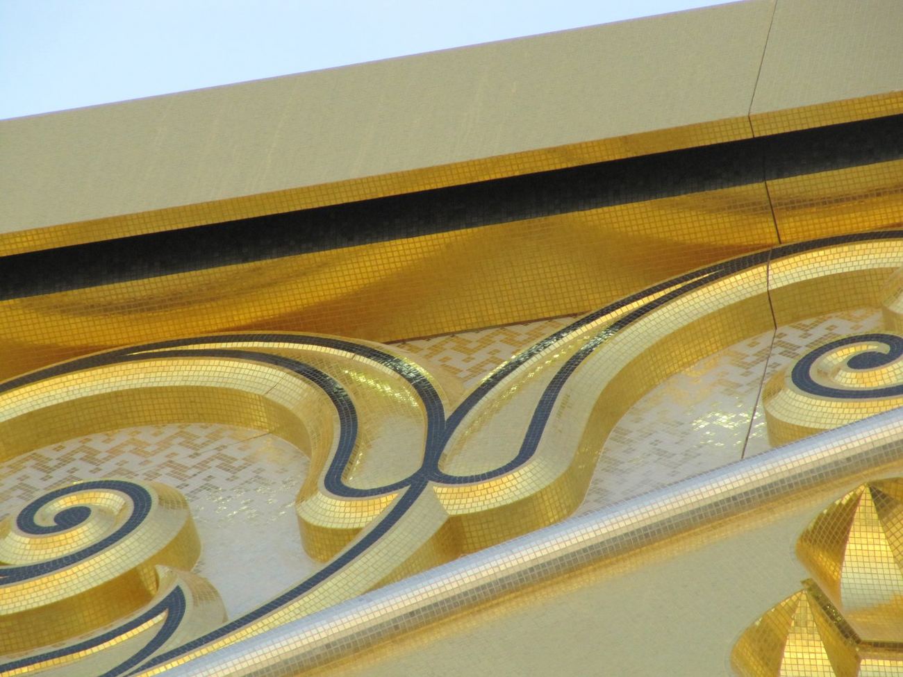 Close view of a gold mosaic seam curving across a pale panel