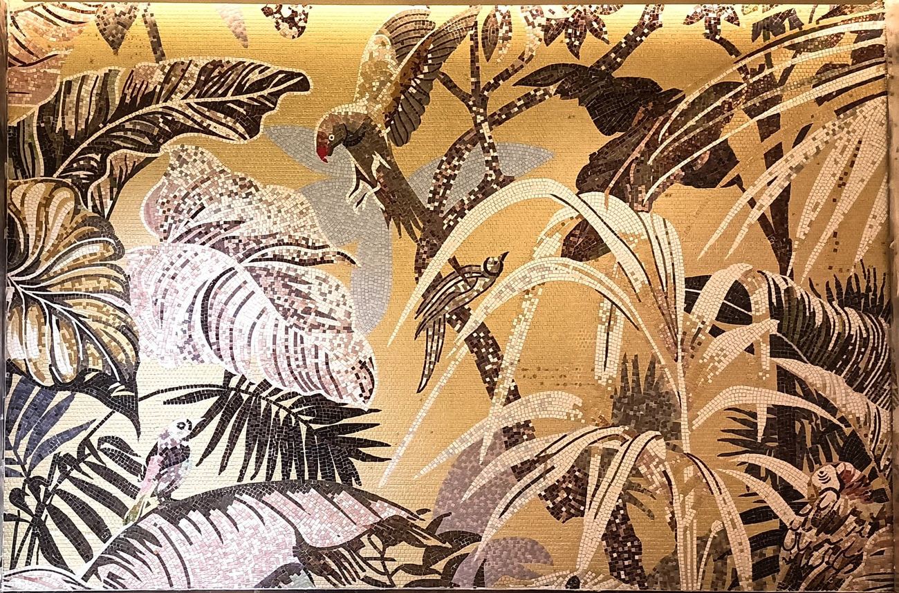 Large mosaic mural of parrots among palm leaves on a gold ground