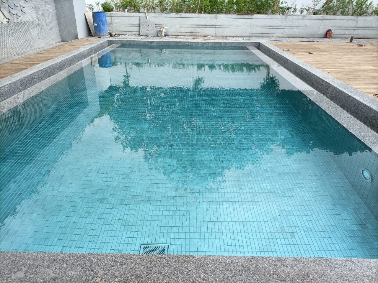 Blue mosaic pool bordered by a timber deck
