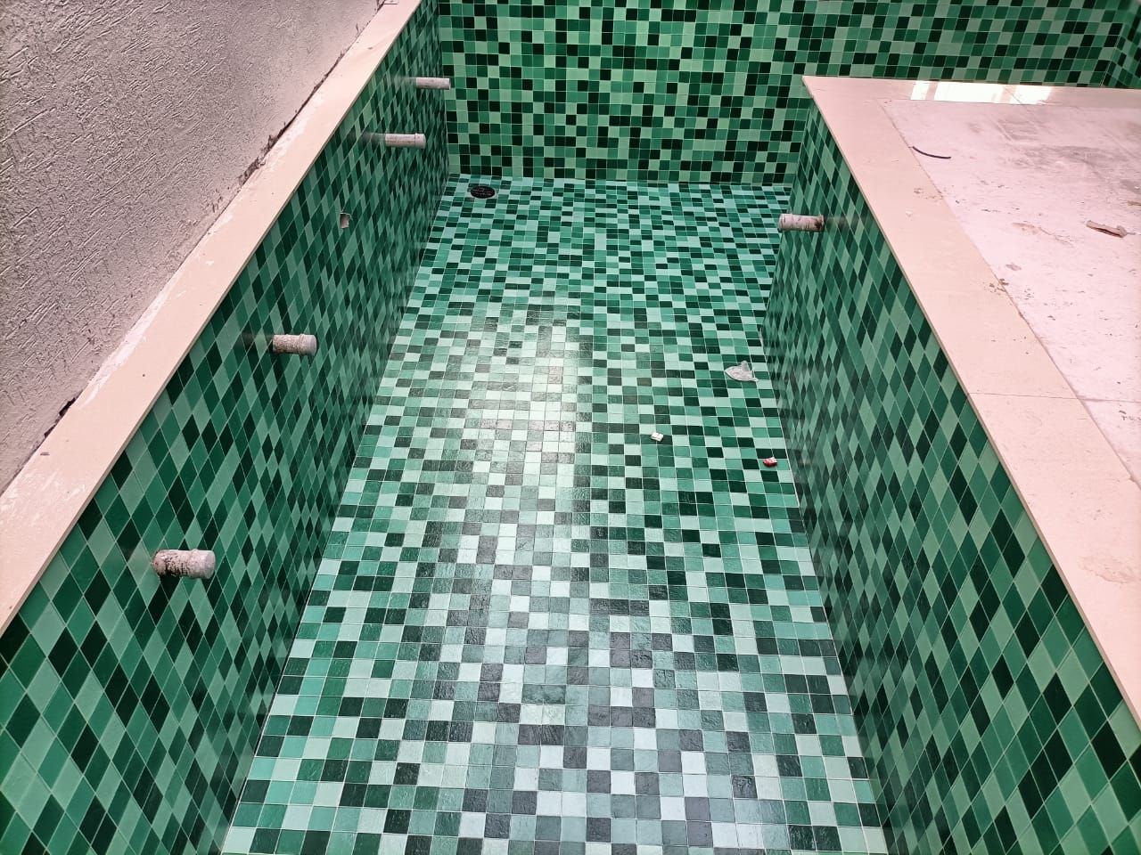 Indoor lap pool lined in dark green mosaic with lane markings