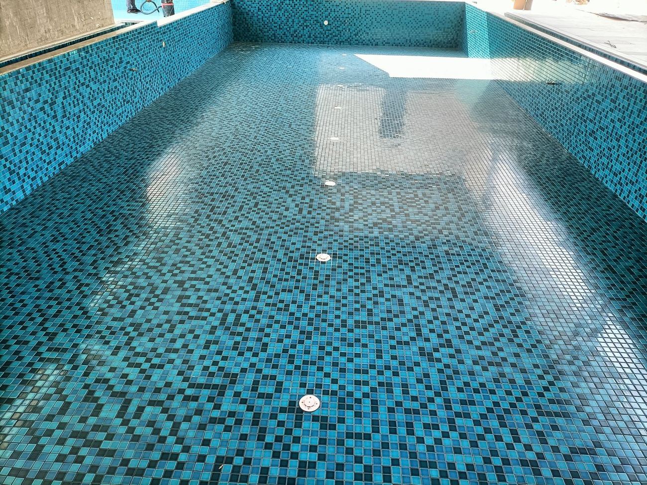 Pool lined in mixed teal glass mosaic with a shallow shelf