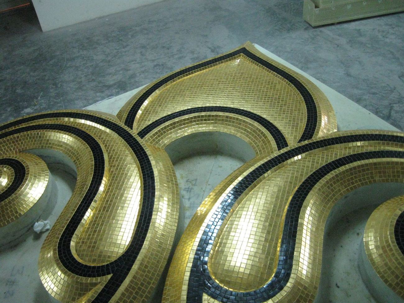 Interlacing gold ribbon ornament outlined in dark blue mosaic