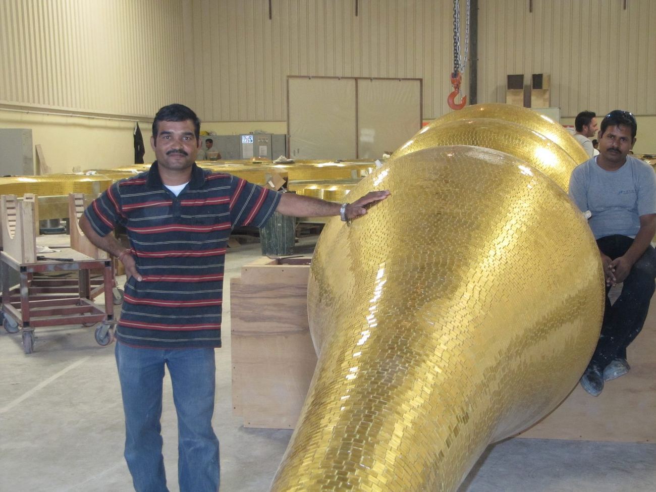 A worker beside a large formed gold mosaic element